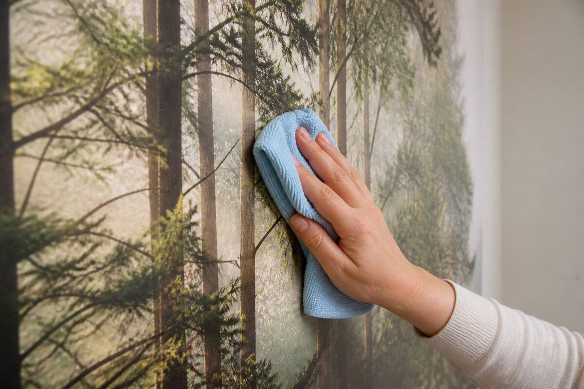 Iemand maakt fotobehang schoon met een zachte microvezeldoek zonder hard te wrijven